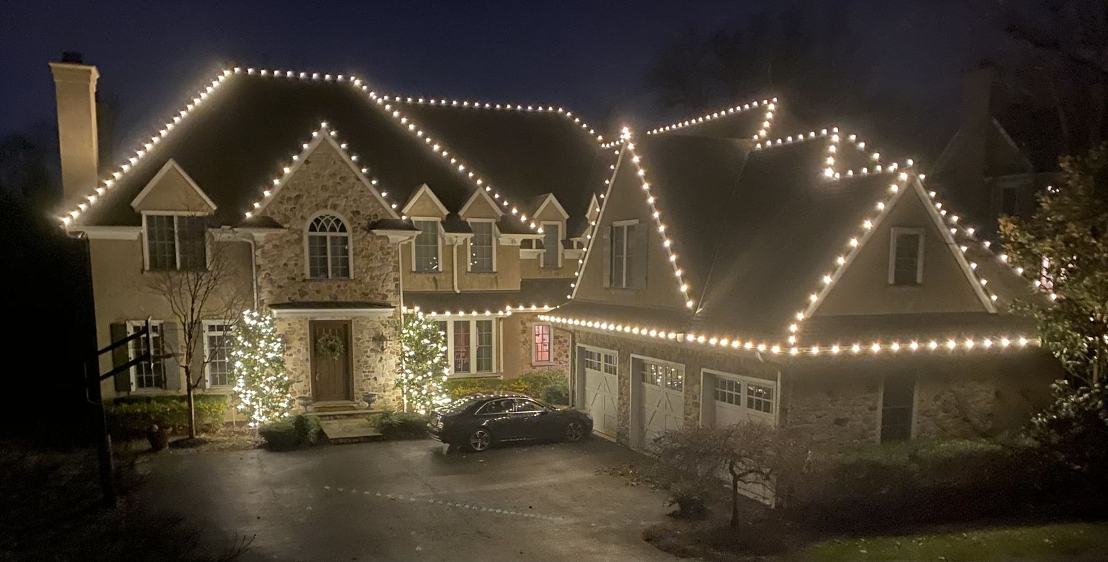 Holiday lighting on a brick colonial with wreaths