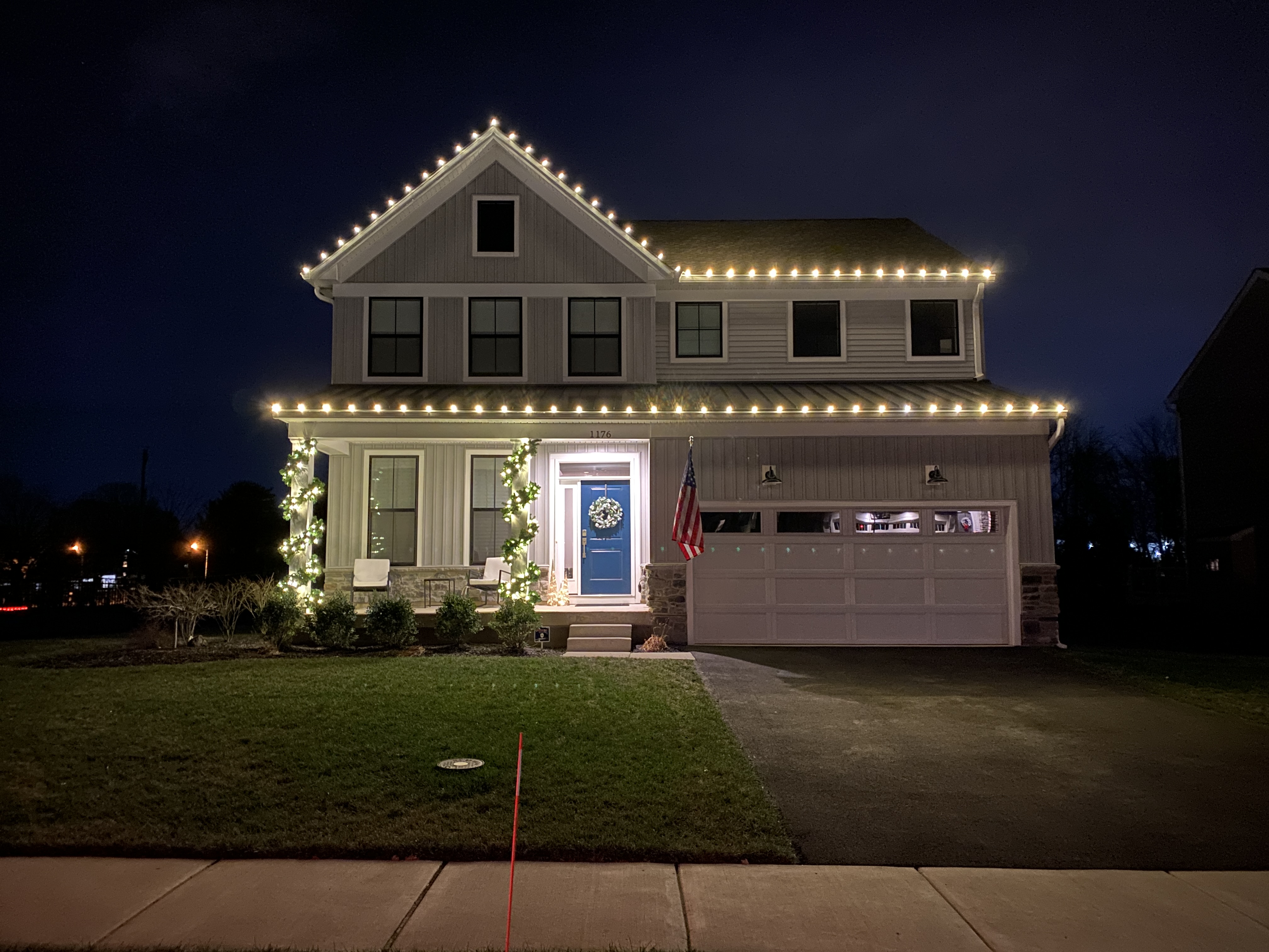 Warm-white Christmas roofline lighting with lit garland on columns at a Warminster home